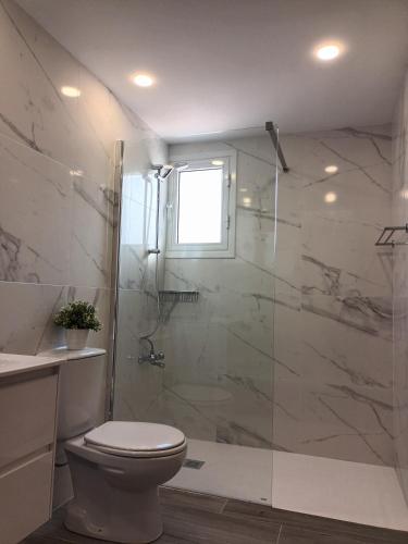 a bathroom with a toilet and a glass shower at Ocean Blue Apartments in Paphos