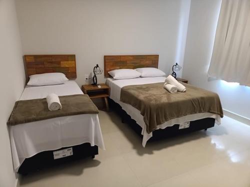 a bedroom with two beds with towels on them at Residencial ponta do sol in Capitólio