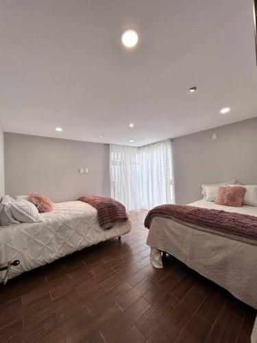 two beds in a room with white walls and wood floors at casa chabela in Tlacolula de Matamoros