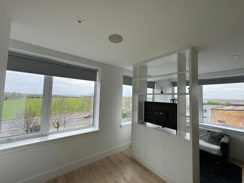 a living room with large windows and a tv at LUXX Apartment & Suites, London Heathrow Airport, Terminal 4, Piccadilly underground Train station nearby! in New Bedfont