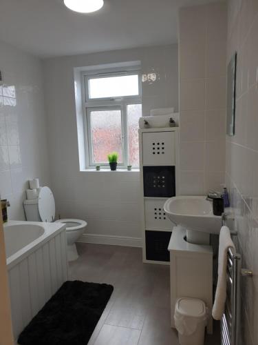 a white bathroom with a tub sink and a toilet at Lenny House in Bradshaw