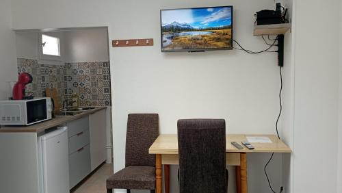 Il comprend une cuisine avec une table et deux chaises ainsi qu'une télévision murale. dans l'établissement Studio Centre ville Claye Souilly Parking communal Gratuit, à Claye-Souilly