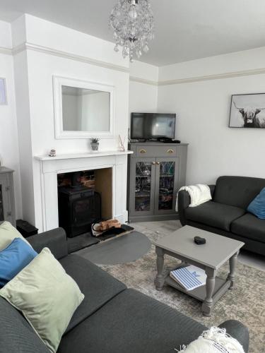 a living room with a couch and a fireplace at Sea Salt Cottage - Mins to beach & shops Dog Friendly in Deal