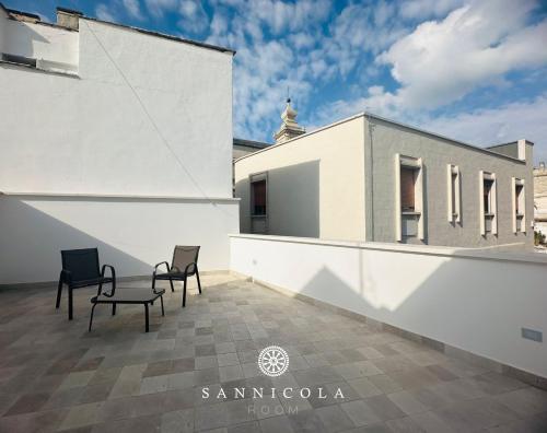a patio with two chairs and a white building at San Nicola Room e spa in Gravina in Puglia
