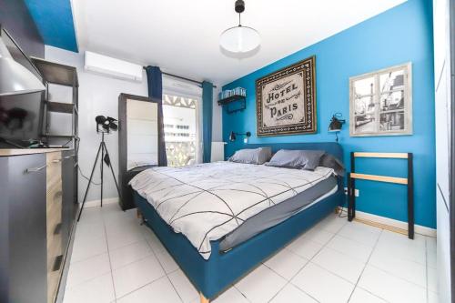 ein blaues Schlafzimmer mit einem Bett und einem Fernseher in der Unterkunft T2 Cubano Montpellier Parking Proche Plages in Montpellier