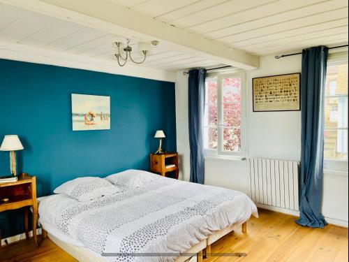 une chambre avec un mur bleu et un lit dans l'établissement Maison mer, jardin, plage, forêt, à Villerville