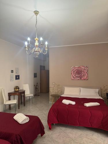 a bedroom with a red bed and a chandelier at B&B Rose Antiche Sicily in Partinico