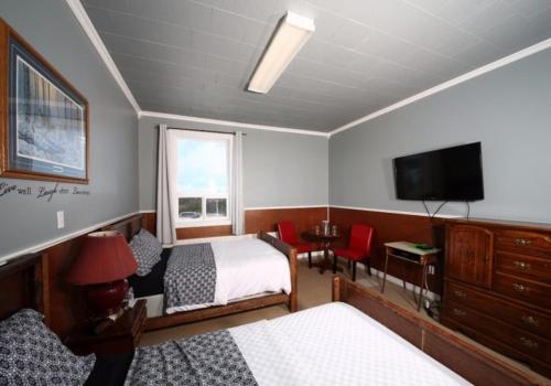 1 dormitorio con 2 camas y TV de pantalla plana en Genevieve Bay Inn en River of Ponds