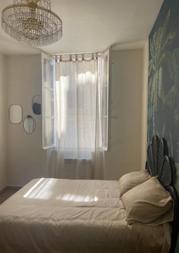 - une chambre avec un lit, une fenêtre et un lustre dans l'établissement Magnifique Suite - Centre ville, à Marseille