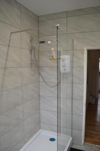 La salle de bains est pourvue d'une douche avec une porte en verre. dans l'établissement Three Bedroom Flat, Camborne Avenue W13, à Londres