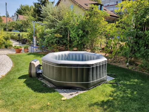 日內瓦的住宿－Appartement pour un couple, jacuzzi en été, jardin，坐在院子里的草上的一个热水浴缸