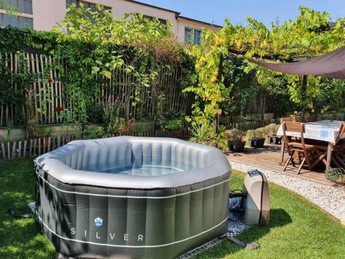 Appartement pour un couple, jacuzzi en été, jardin في جنيف: حديقة خلفية مع حوض استحمام ساخن في العشب