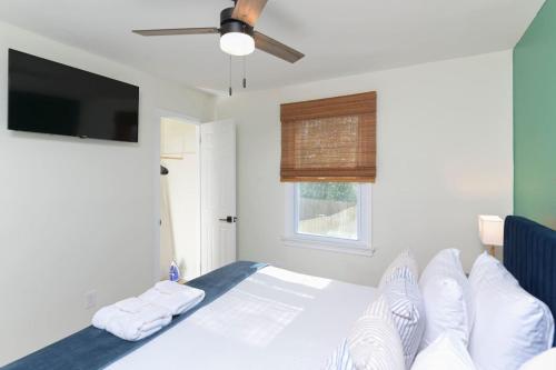 a bedroom with a bed with white sheets and a flat screen tv at Stadium View Stay - Rosewood in Columbia