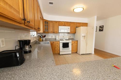 uma cozinha com armários de madeira e um frigorífico branco em Elegant & Spacious 3-bed Gem mins to NYC em Jersey City