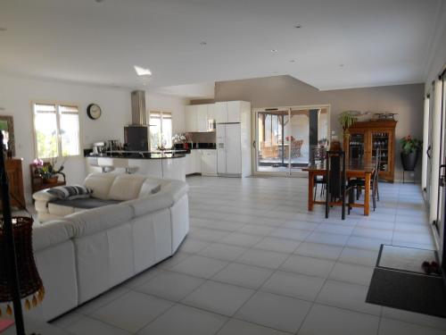 a living room with a white couch and a kitchen at Maison Chauvin in Château-du-Loir