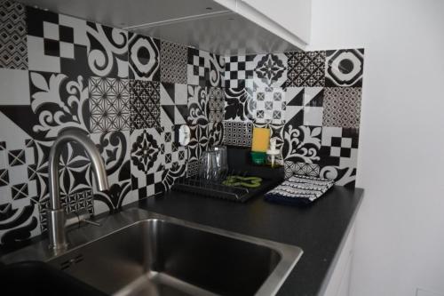 a kitchen with a sink and black and white tiles at Apartamenty Słoneczny Wieczór in Braniewo