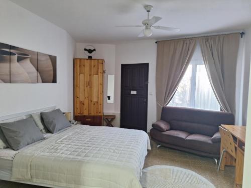 a bedroom with a bed and a couch and a window at Dekel in Arad