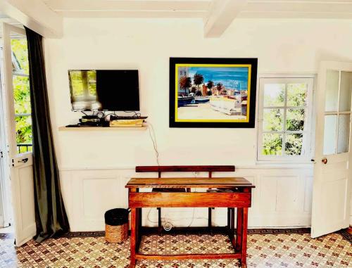 une pièce avec un bureau et une télévision sur un mur dans l'établissement Maison mer, jardin, plage, forêt, à Villerville