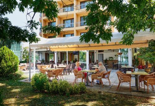 two people sitting at tables in front of a building at Paradise Hotel & Relax Center in Pomorie