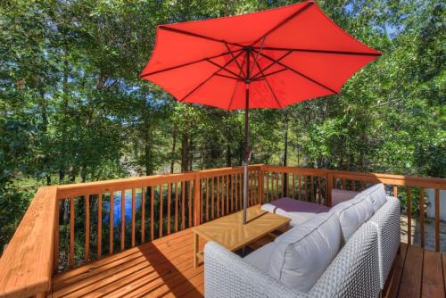 a wooden deck with a red umbrella and white chairs at Pondside at Sweetoak in Columbia
