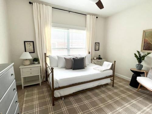 um quarto com uma cama com lençóis brancos e uma janela em The Congaree Cottage em Cayce