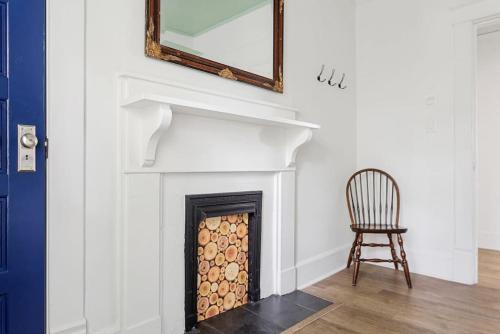 a room with a fireplace with a mirror and a chair at Urban Farmhouse-Sleeps 8 in West Columbia