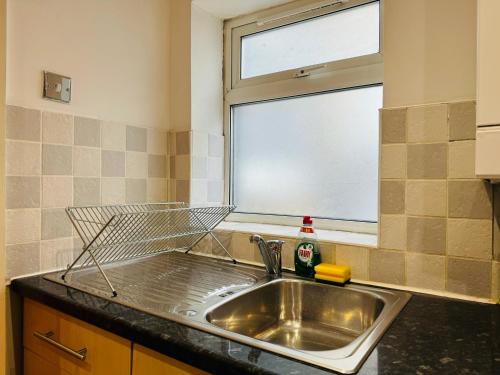a kitchen sink with a dish rack next to a window at Falcon - 2 Bedroom Ground floor flat in Central London in London