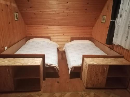 two beds in a wooden room with two tables at Vikendica Studenac in Bajina Bašta