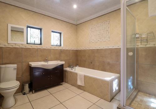 a bathroom with a toilet and a tub and a sink at The Victoria House in Ficksburg