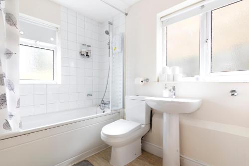 a white bathroom with a toilet and a sink at Detached 4-Bed House near Heathrow in Egham