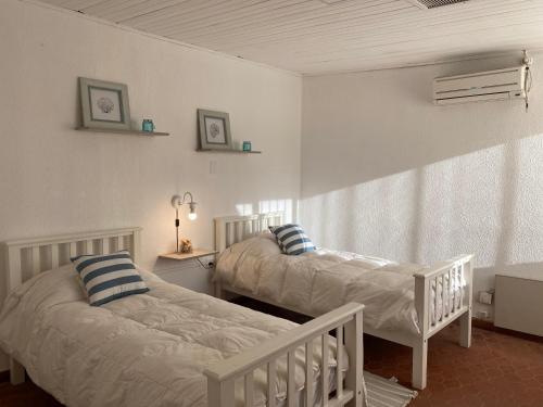 two beds in a room with white walls at Las Marias house in Mendoza
