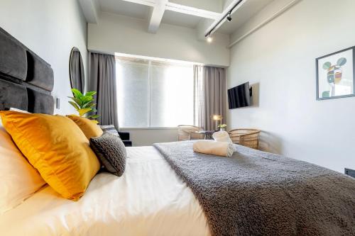 a bedroom with a large bed with yellow pillows at Smart, Contemporary Designed Apartment in Cape Town