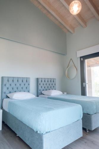 two beds in a bedroom with blue sheets at Carpe Diem Moursia House in Liapades