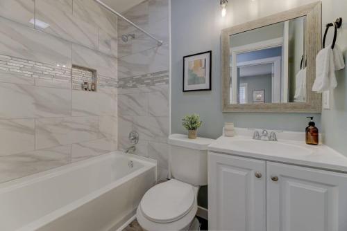 a white bathroom with a sink and a toilet and a tub at Ft. Jackson Family Abode in Columbia