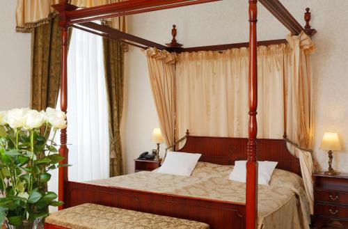 a bedroom with a four poster bed with curtains at Hotel Vila Livia in Karlovy Vary