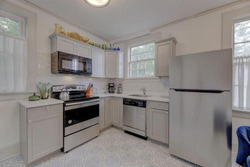 a kitchen with white cabinets and a refrigerator at The Gem of Bull St. Downstairs in Columbia