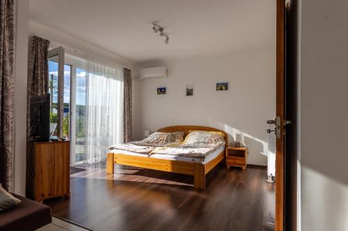 a bedroom with a bed and a large window at Szabolcs Apartments in Demjén