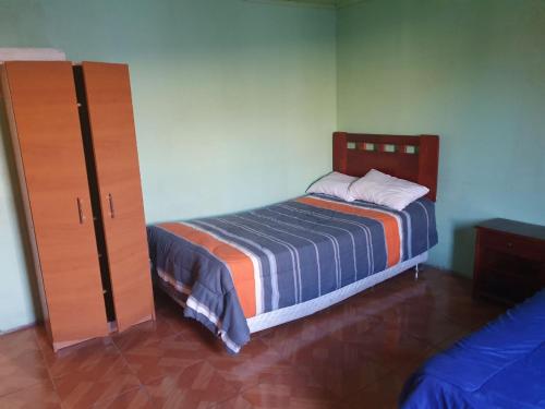 um quarto com uma cama e um armário de madeira em Acogedora Habitación San Pedro de Atacama em Toconao