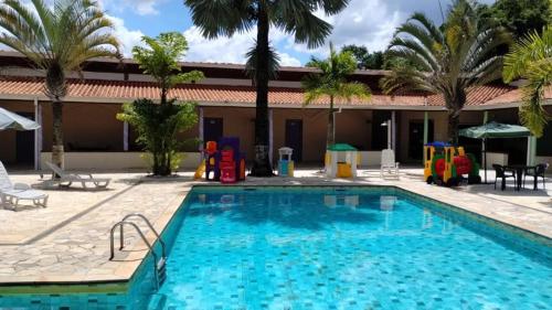 a swimming pool with a playground next to a resort at RIACHI POUSADA in Atibaia