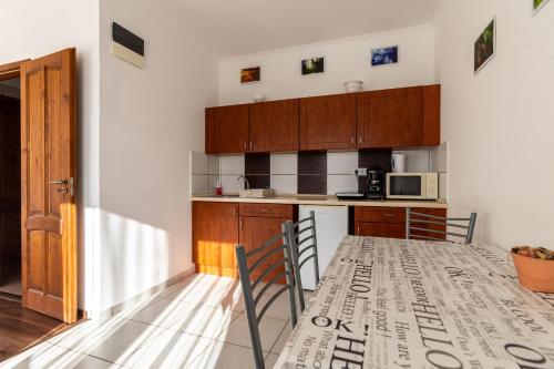 a kitchen with wooden cabinets and a table with chairs at Szabolcs Apartments in Demjén