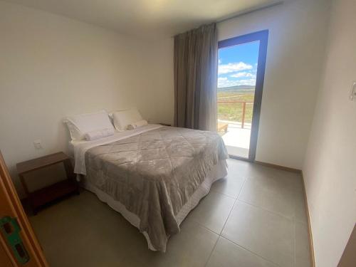 a bedroom with a bed and a sliding glass door at Vila beija-flor prime / apt 02 in Mucugê