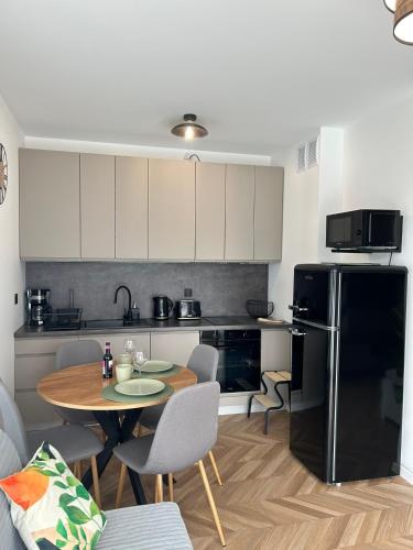 a kitchen with a table and a black refrigerator at Apartament Holiday Mini Gold in Rewal