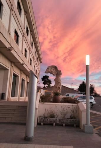 a statue in front of a building with a sunset at Hotel Sercotel Cuatro Postes in Avila