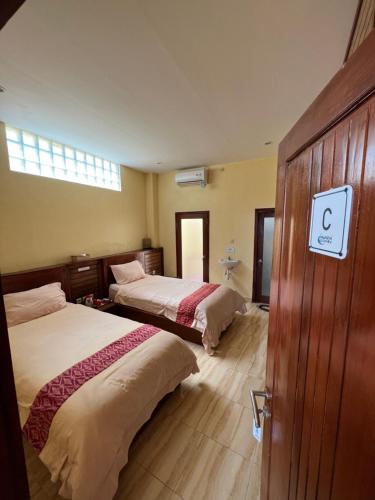 a bedroom with two beds and a door with a sign on it at Nawasena Ocean View in Toyapakeh