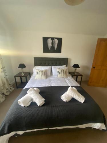 1 dormitorio con 1 cama grande con almohadas blancas en THE ENCHANTED COTTAGE en Rolleston