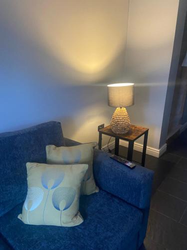 a blue couch with pillows and a table with a lamp at THE ENCHANTED COTTAGE in Rolleston
