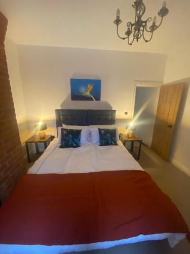 a bedroom with a large bed and two tables at THE ENCHANTED COTTAGE in Rolleston