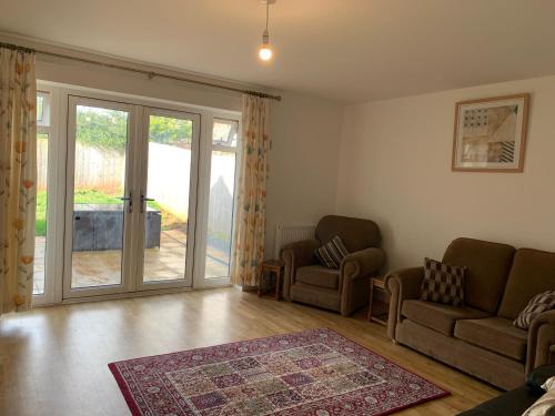 a living room with a couch and chairs and a sliding glass door at The Chestnuts in Winscombe