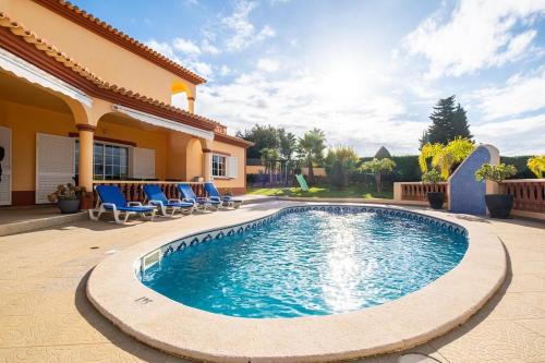 a swimming pool with chairs and a house at Villa Glória in Praia do Carvoeiro