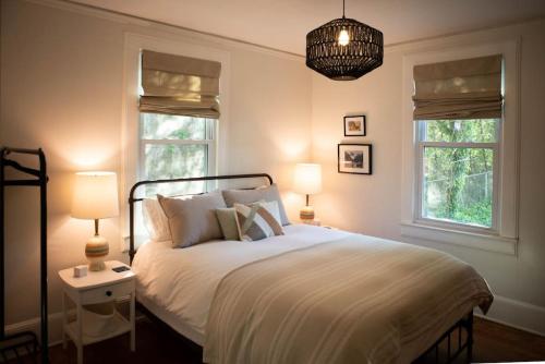 1 Schlafzimmer mit einem weißen Bett und 2 Fenstern in der Unterkunft Cozy Blue Door Farmhouse in Columbia